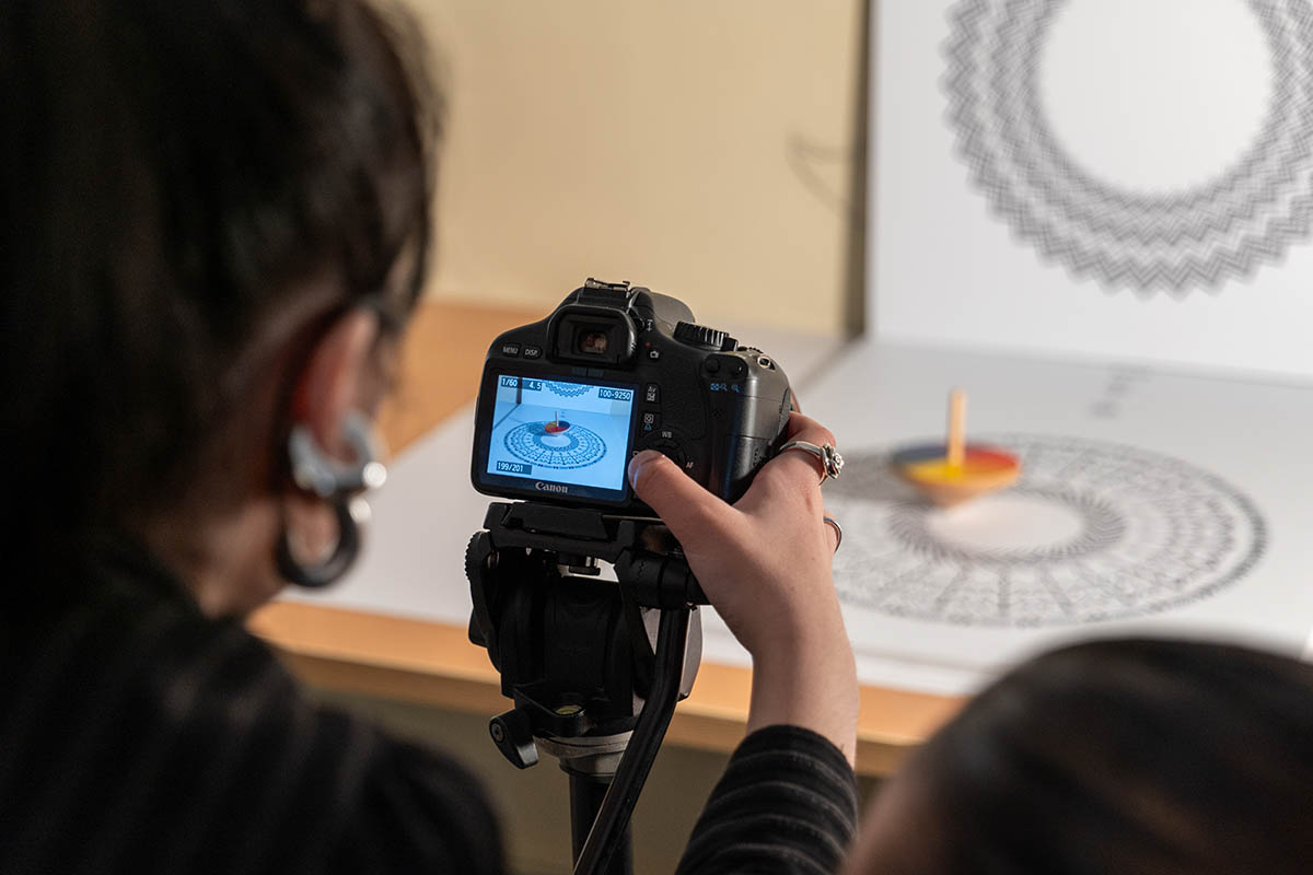 Laboratorio di fotografia: una studnetessa inquadra l'oggetto con la macchina fotografica